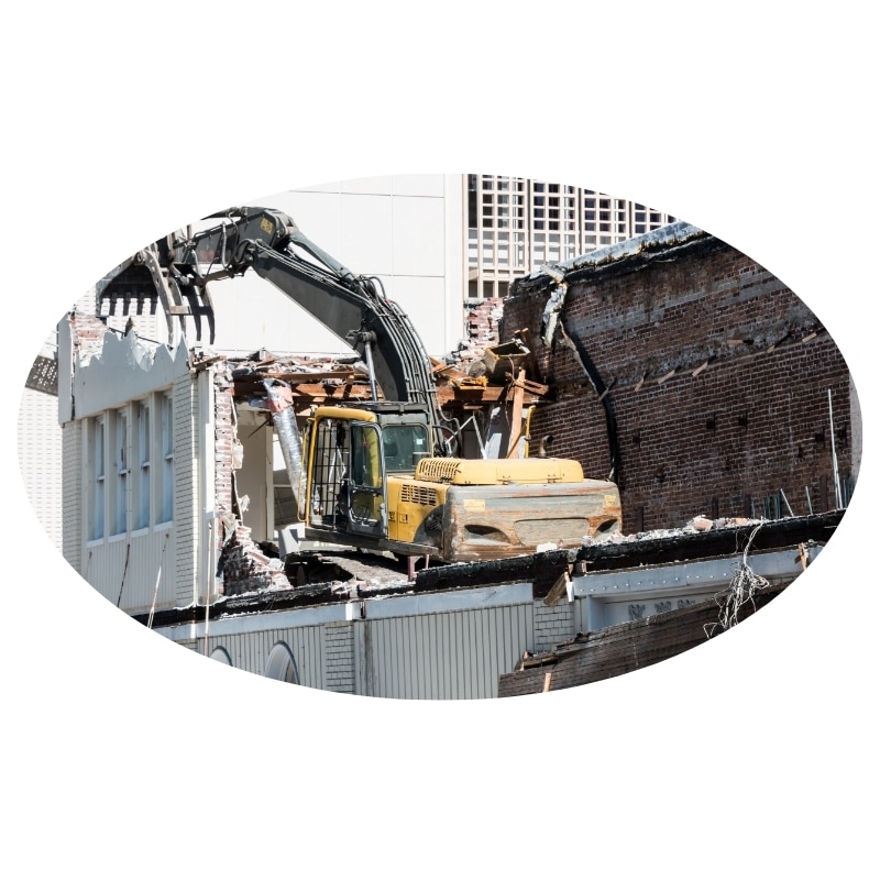 Commercial Demolition: Close-up of an excavator bucket tearing down a building.