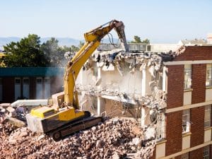 a bulldozer demolishing a commercial building with the guidance of structural assessment