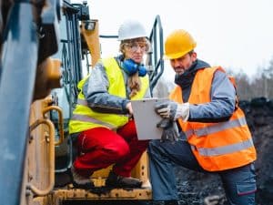 Excavation techniques with workers wearing PPE as a safety measure on a construction site in hot weather.