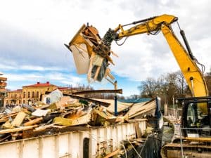 Heavy machinery sorting wood and debris at a construction site, emphasizing eco-friendly demolition dust suppression solutions.