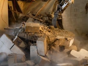 DIY demolition work with machinery, creating dust and debris.