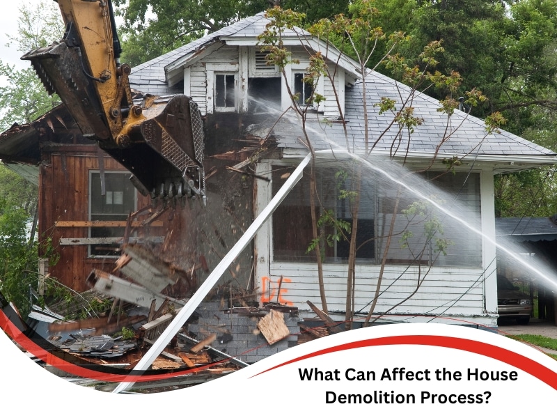 Excavator tearing down timber walls during the house demolition process with water sprayed for dust control