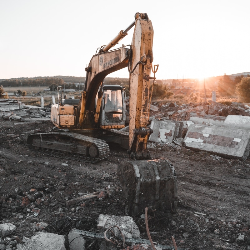 Excavator at demolition site during sunrise, used for excavation Newcastle projects.