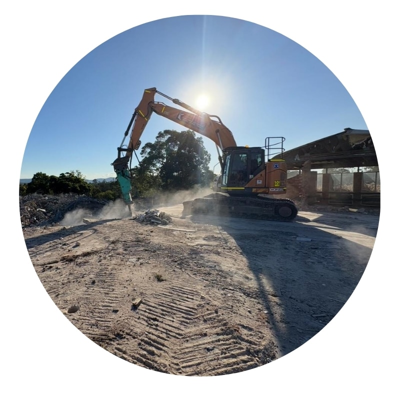 Experienced demolition contractor using excavator with hydraulic breaker on construction site.