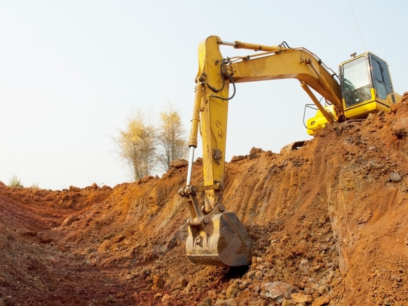 ellow excavator digging soil slope to demonstrate different types of excavation.