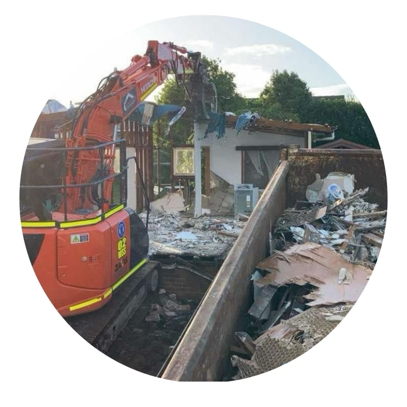 House demolition contractor using excavator to tear down residential structure.