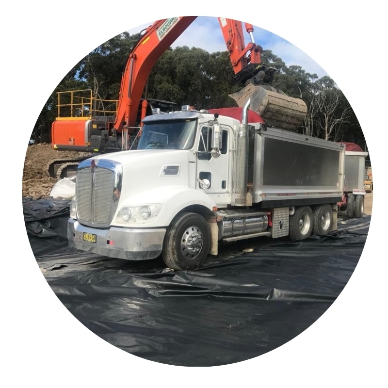 Truck loading soil at construction site for occupational hygiene & environmental monitoring compliance and site safety.