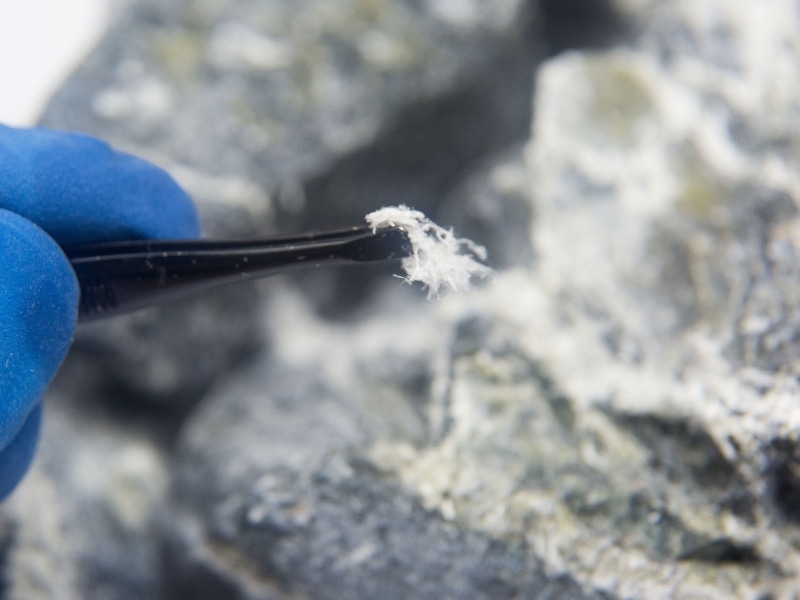 Gloved hand holding asbestos fibre during Asbestos Paint Removal